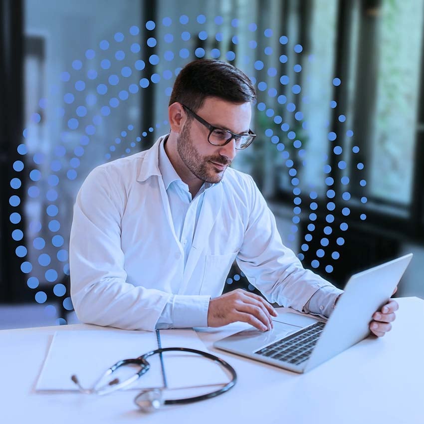 Doctor sitting at a desk with his laptop, using ReviveCS software solution