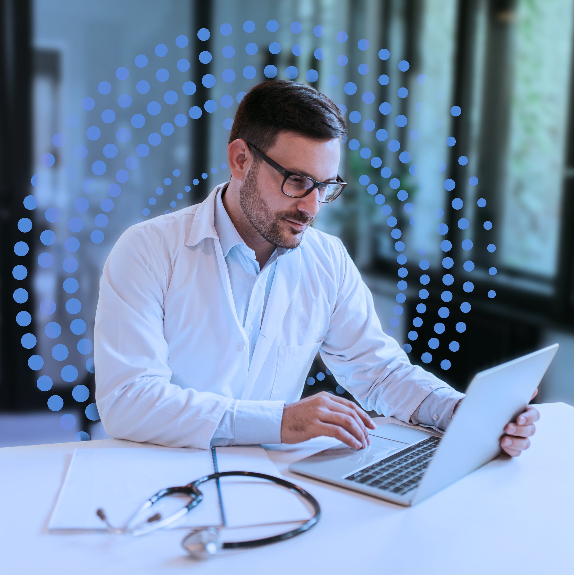 Doctor sitting at a desk with his laptop, using ReviveCS software solution.