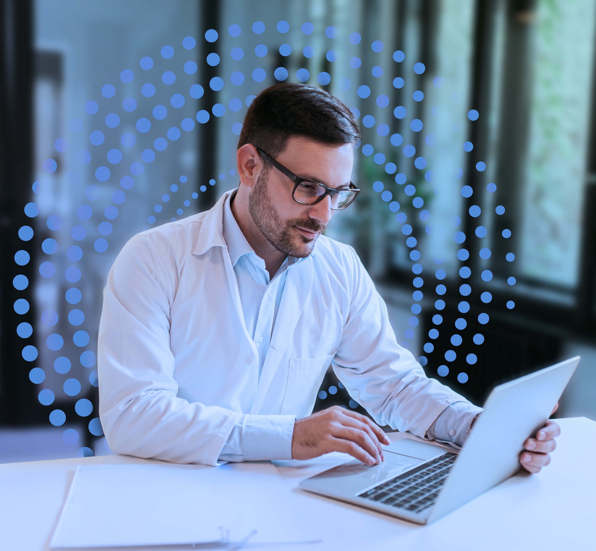 Doctor sitting at a desk with his laptop, using ReviveCS software solution.